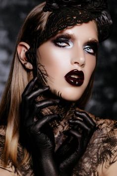 a woman with black makeup and gloves on her face