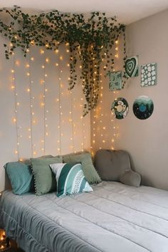 a bed sitting under a tree with lights on the wall and pillows in front of it