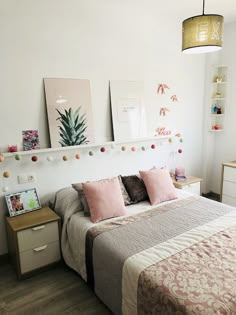 a bed room with a neatly made bed and some pictures on the wall above it