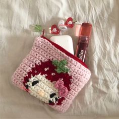 a crocheted bag with lipstick, toothbrushes and other items on it