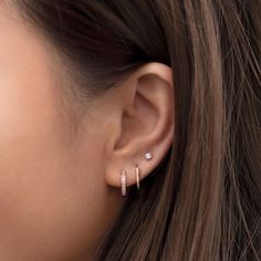 a close up view of a woman's ear with two diamond earrings