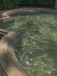 an empty swimming pool in the middle of a park with water flowing from it's sides