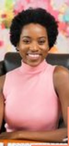 a woman sitting at a desk with her arms crossed in front of her chest and smiling