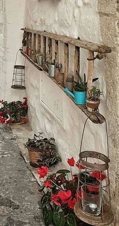 flowers and plants are on the ledge of an old building with hanging planters filled with potted plants