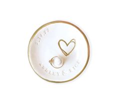 a white and gold plate with two hearts on the front, one heart is in the middle