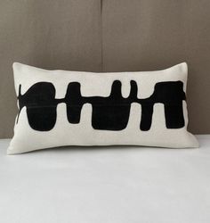 a black and white pillow sitting on top of a bed