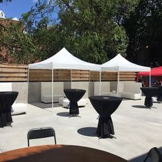 tables and chairs are set up for an outdoor event with white tents in the background