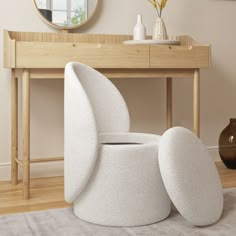 a white chair sitting on top of a wooden table next to a mirror and vase