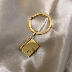 a gold keychain on a white satin background