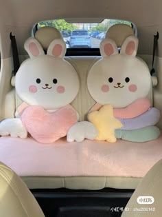 two stuffed animals sitting in the back seat of a car with one holding a star