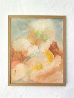 an abstract painting hangs on the wall next to a white wall with a wooden frame