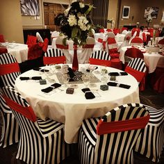 a dining room set up with red and white striped chairs, black and white tablecloths and centerpieces