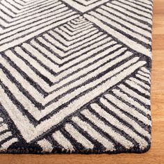 a black and white rug on a wooden floor with a wood floor in the background