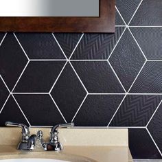 a bathroom sink sitting under a mirror next to a wall covered in black and white tiles