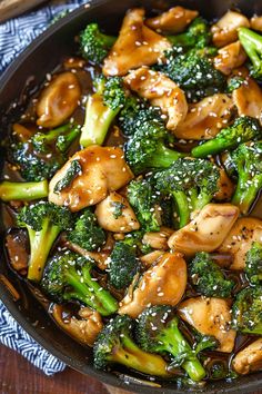 chicken and broccoli stir fry in a skillet with sesame seeds on the side