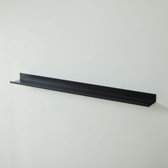 a black shelf mounted to the side of a white wall