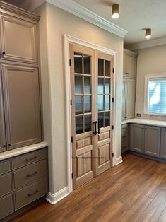 an empty kitchen with wooden floors and gray cupboards on either side of the door