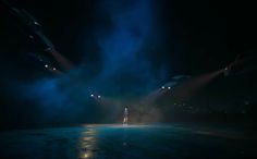 a person standing in the middle of a dark street at night with lights shining on them