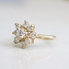 a yellow gold ring with three diamonds on it's side, sitting on a white surface