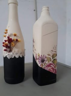 two vases with flowers painted on them sitting next to each other