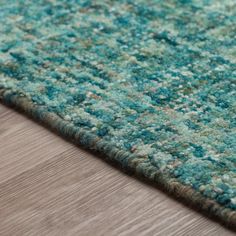 a close up view of a blue and green rug on a wooden floor with wood floors