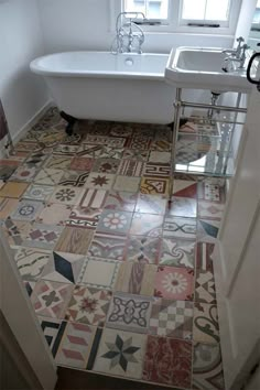 a bath tub sitting next to a white sink in a bathroom with tiled flooring