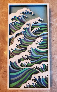 a wooden cutout of a wave in blue, green and white