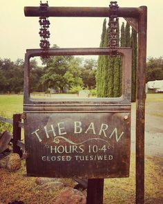 the barn hours 10 - 4 closed sign in front of an empty field with trees