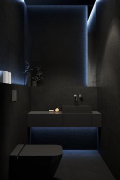 a black bathroom with blue lighting on the ceiling and counter top, along with two sinks