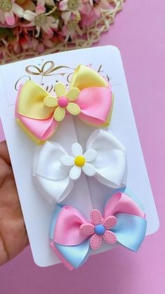 three different colored bows on top of each other in front of a pink and white background