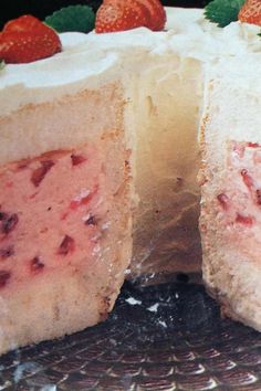 a cake with white frosting and strawberries on top is cut in half to show the inside