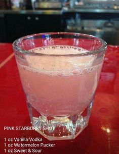 a glass filled with liquid sitting on top of a red table