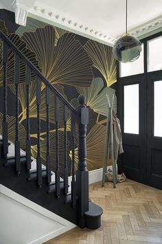 a stair case next to a black door in a room with wooden floors and wallpaper