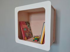 there is a book shelf with books on it and a rubix cube next to it