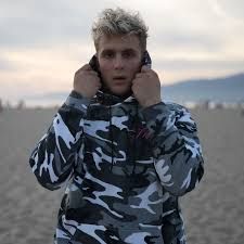 a man on the beach talking on his cell phone while wearing a camo jacket