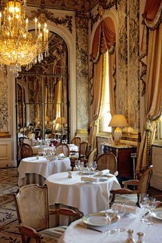 a fancy dining room with chandeliers and white table cloths on the tables