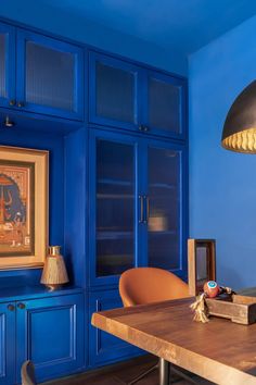 a room with blue painted walls and furniture in it, including a wooden dining table