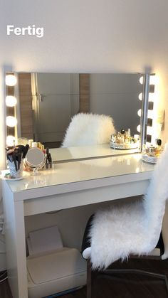 a white vanity with lights on it and a fur chair in front of the mirror