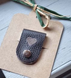 a leather case with a heart on it sitting on a piece of paper next to a green ribbon