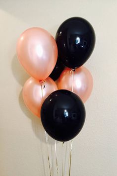 some black and pink balloons are hanging on the wall