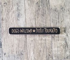 a black and white sign that says dogs welcome people tolerated on wood planks