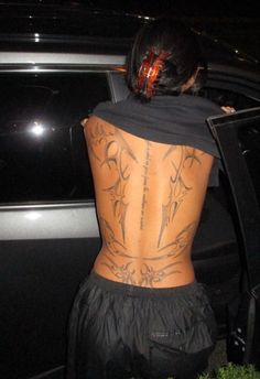 the back of a woman's body with tattoos on it