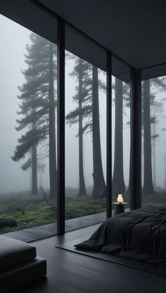 a bed sitting in front of a window next to a forest filled with tall trees