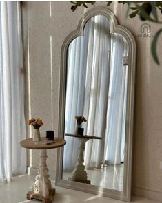 a mirror sitting on top of a table next to a vase with flowers in it