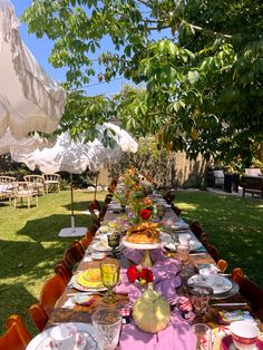 a long table is set up with plates and cups for an outdoor dinner in the garden