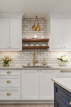 a kitchen with white cabinets and gold hardware on the handles, counter tops and drawers