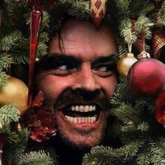 an image of a man peeking out from behind a christmas tree