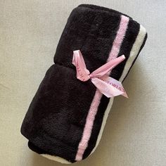 two towels wrapped in black and pink with a ribbon tied around the edges, sitting on a white surface