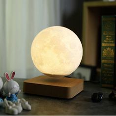 the moon lamp is sitting on top of a table next to some figurines