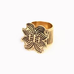 a gold and black flower ring on a white background